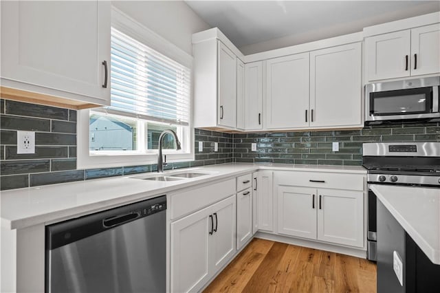 1933 SW Merryman Dr, Lees Summit, MO 64082 - kitchen featuring appliances with stainless steel finishes, a sink, light countertops, white cabinetry, and light wood-style floors