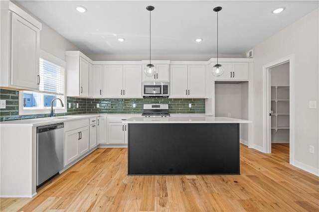 1933 SW Merryman Dr, Lees Summit, MO 64082 - kitchen with stainless steel appliances, a sink, white cabinets, light countertops, and light wood finished floors