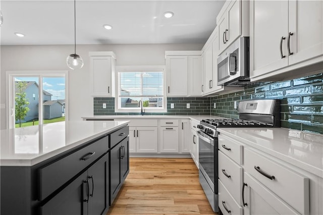 kitchen featuring white cabinets, decorative light fixtures, light hardwood / wood-style floors, and appliances with stainless steel finishes