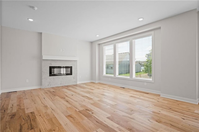 1933 SW Merryman Dr, Lees Summit, MO 64082 - unfurnished living room with light wood-style flooring, a glass covered fireplace, baseboards, and recessed lighting