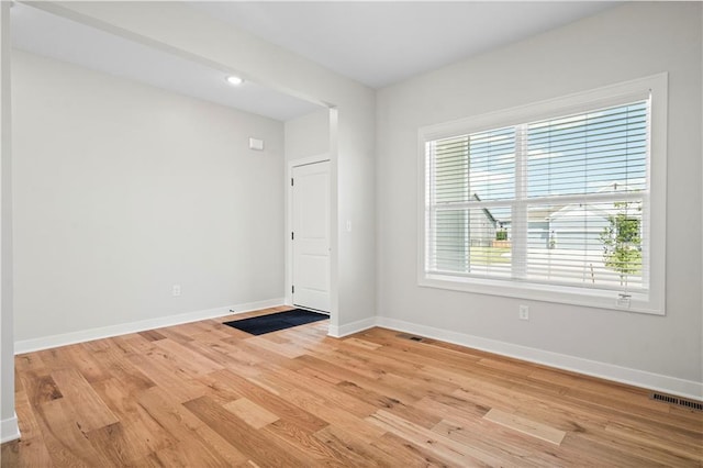 empty room with plenty of natural light and light hardwood / wood-style floors