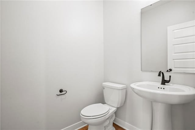 bathroom with wood-type flooring, toilet, and sink