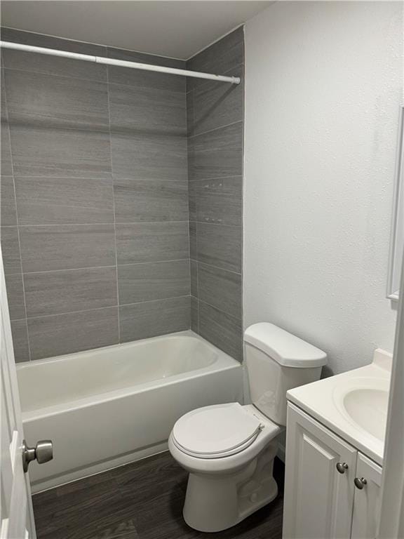 full bathroom featuring vanity, wood-type flooring, tiled shower / bath combo, and toilet