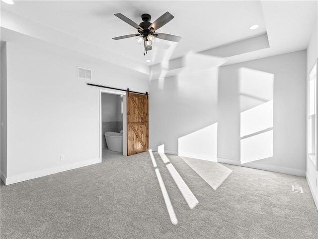 empty room with carpet, ceiling fan, and a barn door