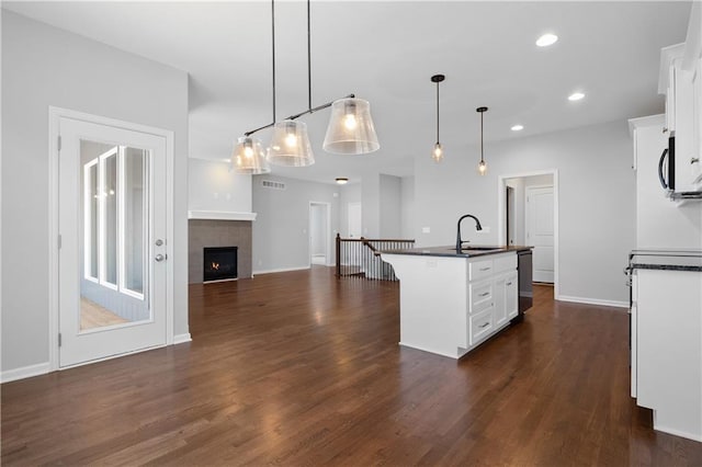 kitchen featuring white cabinetry, dark hardwood / wood-style flooring, an island with sink, and decorative light fixtures