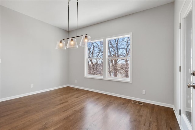 unfurnished dining area with dark wood-type flooring
