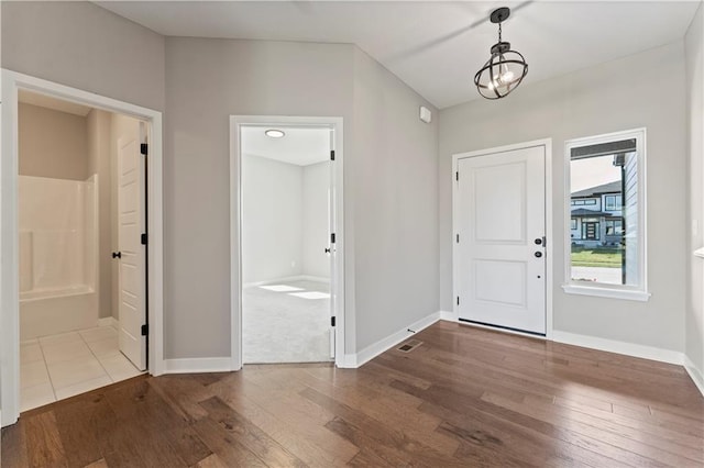 foyer featuring an inviting chandelier, wood finished floors, and baseboards