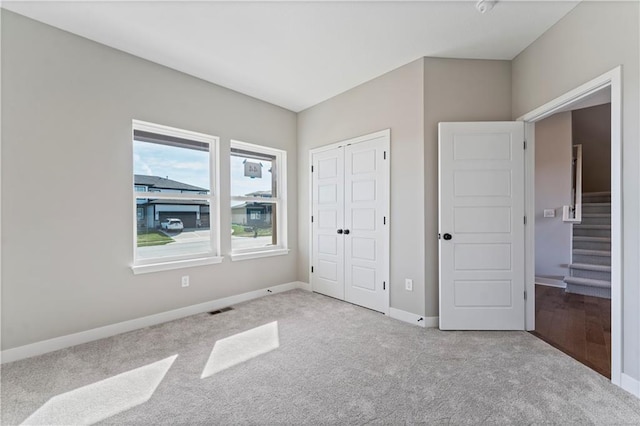 unfurnished bedroom featuring visible vents, a closet, carpet flooring, and baseboards