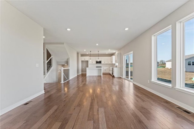 unfurnished living room featuring recessed lighting, visible vents, hardwood / wood-style floors, and plenty of natural light
