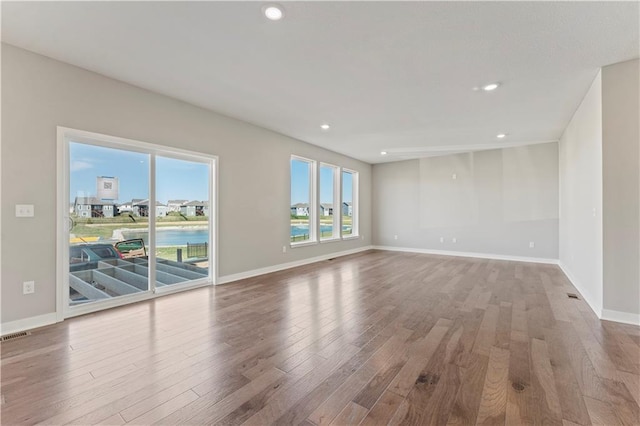 empty room with baseboards, recessed lighting, wood finished floors, and visible vents