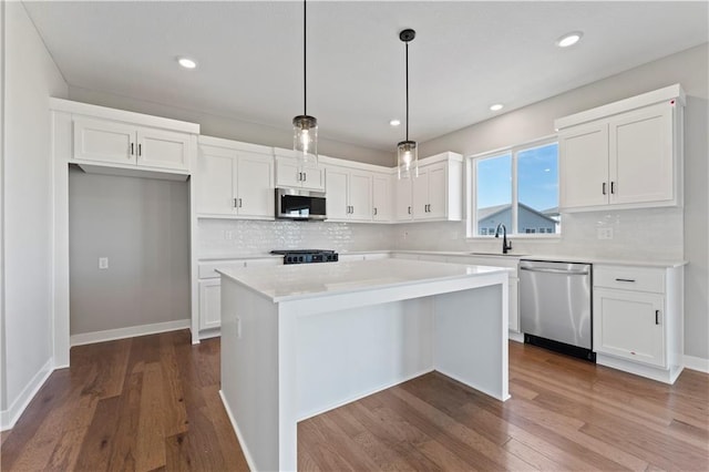 kitchen featuring a sink, stainless steel appliances, dark wood-type flooring, white cabinetry, and a kitchen island