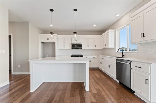 kitchen featuring a sink, tasteful backsplash, dark wood-type flooring, white cabinetry, and appliances with stainless steel finishes