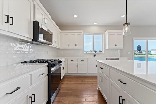 kitchen featuring stainless steel microwave, a sink, light countertops, gas stove, and wood finished floors