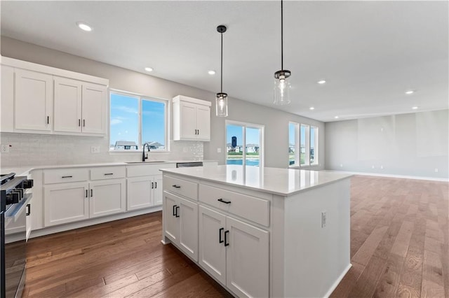 kitchen featuring a wealth of natural light, decorative backsplash, gas stove, and a sink