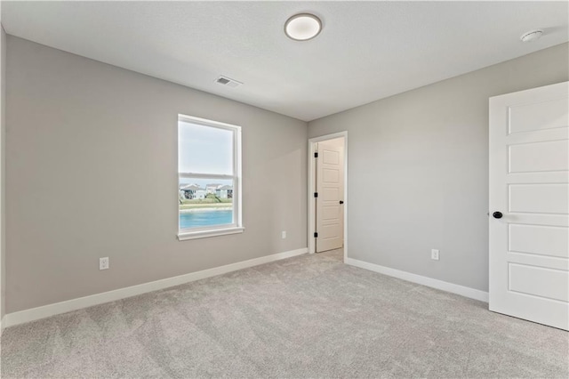 carpeted spare room featuring baseboards and visible vents