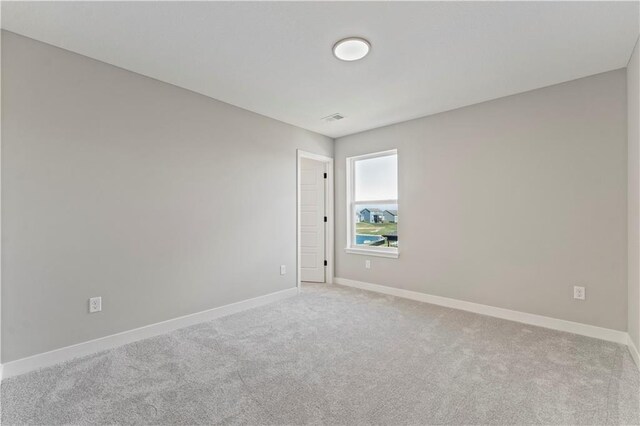carpeted spare room with visible vents and baseboards