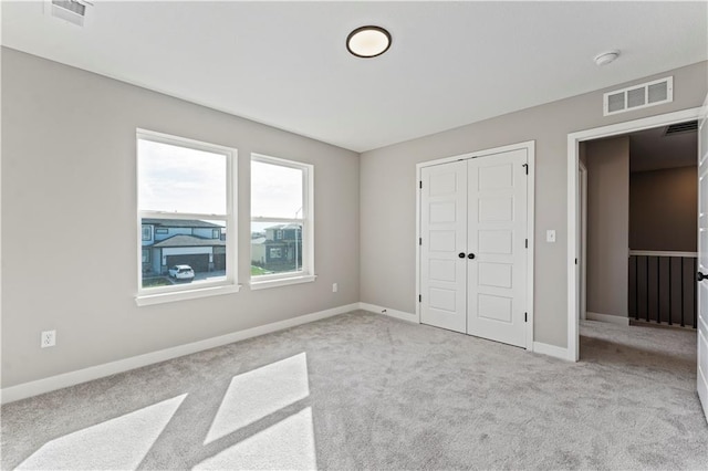 unfurnished bedroom with a closet, visible vents, and carpet