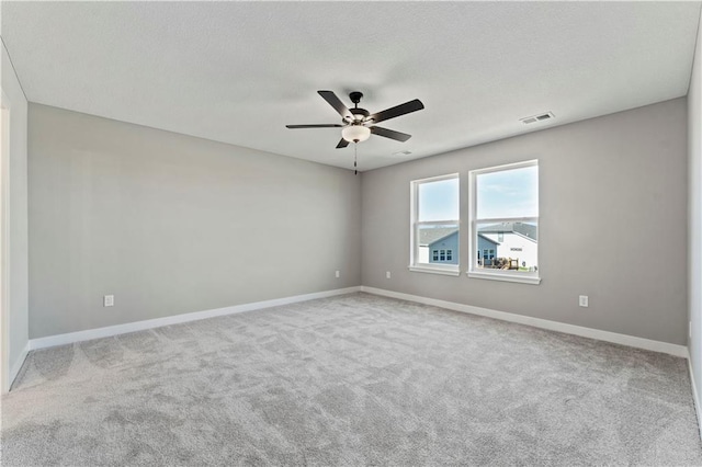 carpeted spare room with visible vents, ceiling fan, and baseboards
