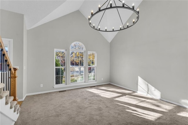 unfurnished living room featuring carpet flooring, high vaulted ceiling, and a notable chandelier