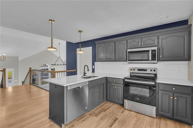 kitchen featuring gray cabinetry, sink, hanging light fixtures, light hardwood / wood-style flooring, and appliances with stainless steel finishes