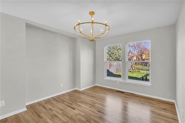 unfurnished room featuring light hardwood / wood-style floors and an inviting chandelier