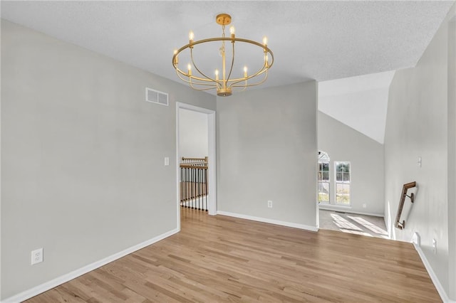 interior space with a notable chandelier, vaulted ceiling, a textured ceiling, and light hardwood / wood-style flooring