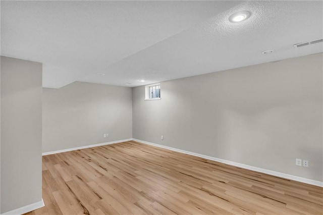 basement with a textured ceiling and light hardwood / wood-style floors