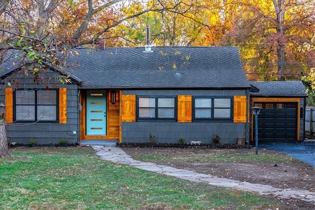 view of front of property featuring a shingled roof, a front lawn, driveway, and an attached garage