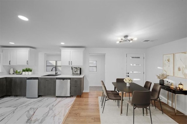 kitchen with light countertops, visible vents, backsplash, a sink, and dishwasher