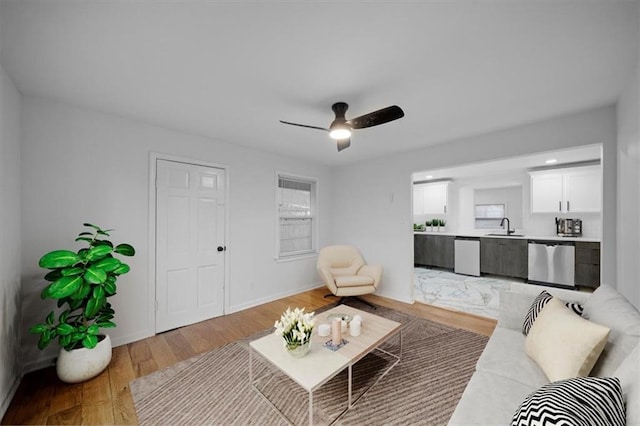 living area featuring light wood-style floors, ceiling fan, and baseboards