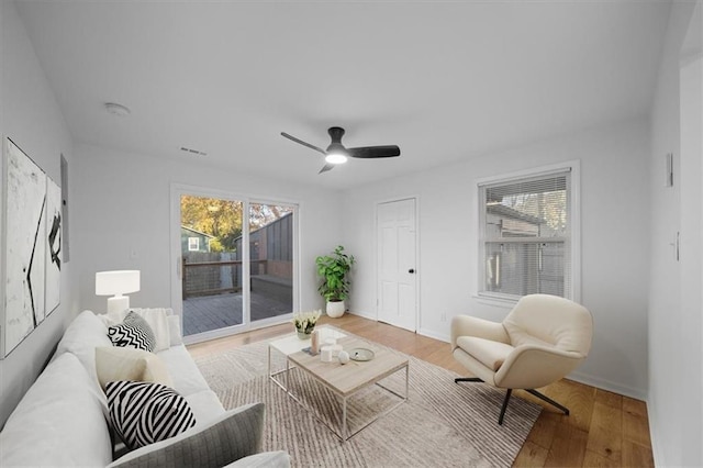 living room featuring visible vents, ceiling fan, light wood-style flooring, and baseboards