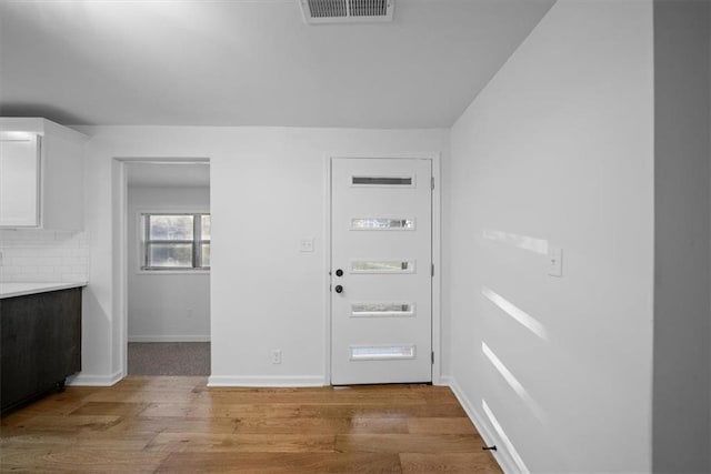 foyer with baseboards, visible vents, and wood finished floors