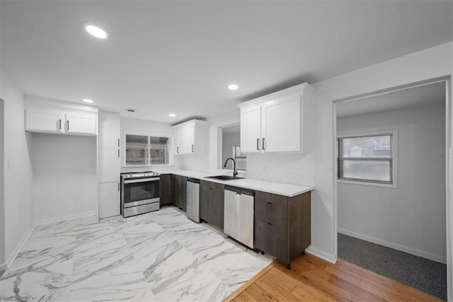 kitchen with white cabinets, backsplash, stainless steel appliances, and a sink