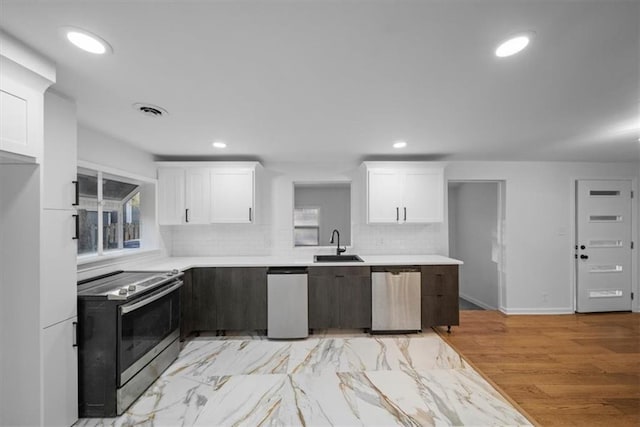 kitchen featuring stainless steel appliances, light countertops, white cabinetry, a sink, and recessed lighting