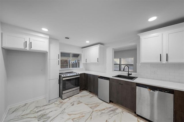 kitchen featuring marble finish floor, appliances with stainless steel finishes, a sink, and light countertops