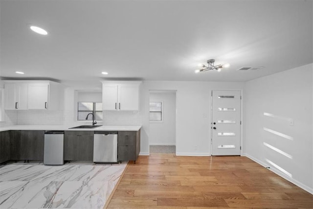 kitchen featuring a sink, visible vents, white cabinets, light countertops, and stainless steel dishwasher