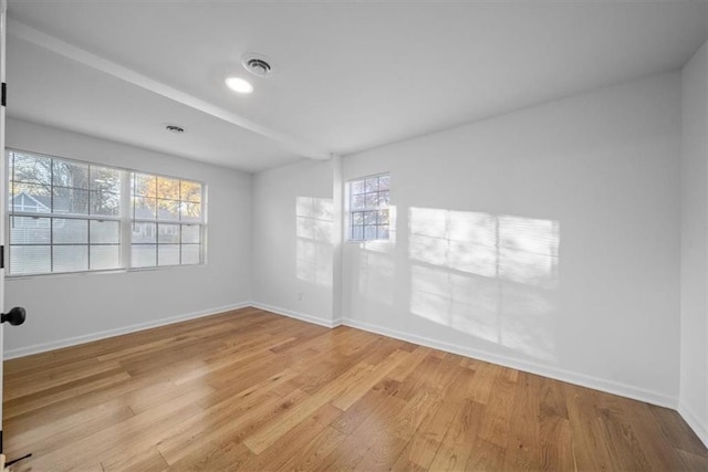 spare room featuring light wood-style flooring, visible vents, and baseboards