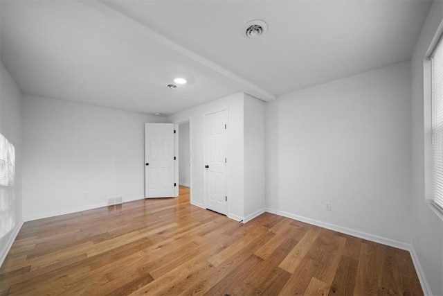 spare room with baseboards, visible vents, and wood finished floors