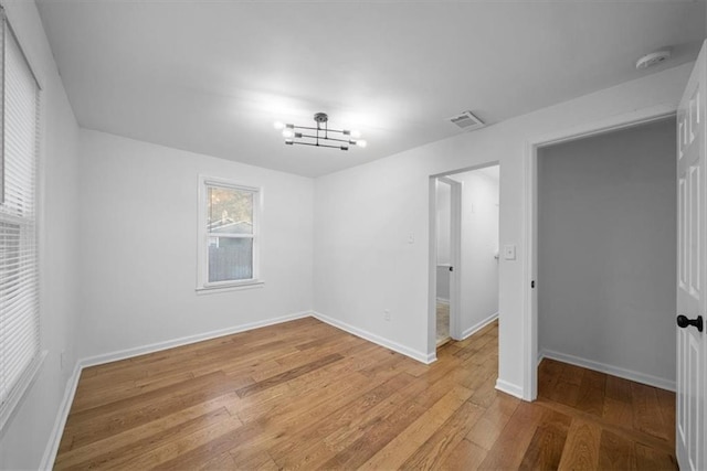 empty room featuring light wood finished floors, visible vents, and baseboards