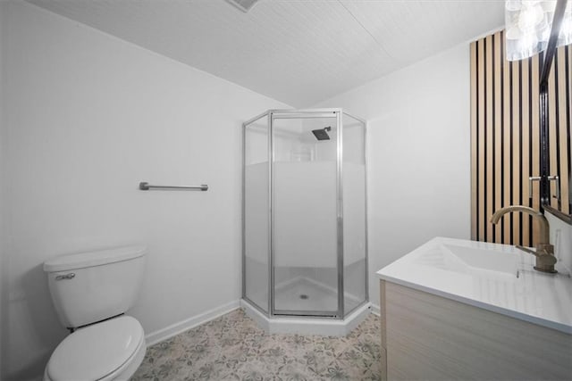 bathroom featuring toilet, a stall shower, vanity, and baseboards