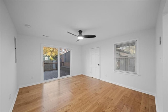 spare room with light wood-style floors, a healthy amount of sunlight, and baseboards