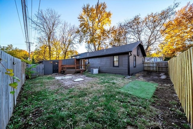 back of house with a fenced backyard, a yard, a deck, and central air condition unit