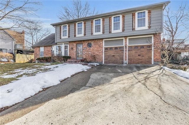 colonial home with a garage, driveway, brick siding, and fence