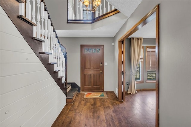 foyer with a notable chandelier, stairway, wood finished floors, and baseboards