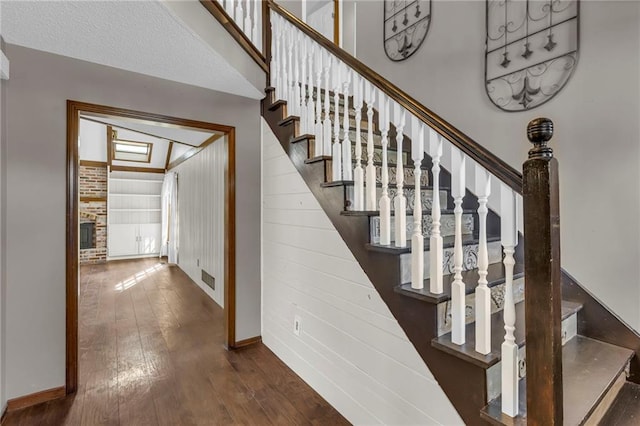 stairs featuring a brick fireplace, visible vents, baseboards, and hardwood / wood-style floors