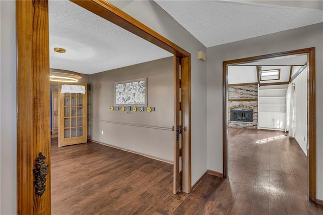 hall with baseboards, dark wood finished floors, and a textured ceiling