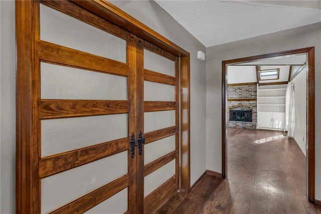 hall with dark wood-type flooring, french doors, a textured ceiling, and baseboards