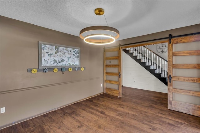 interior space featuring a barn door, a textured ceiling, wood finished floors, and stairs