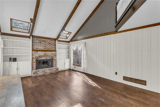 unfurnished living room featuring wood walls, wood finished floors, built in features, a brick fireplace, and lofted ceiling with skylight