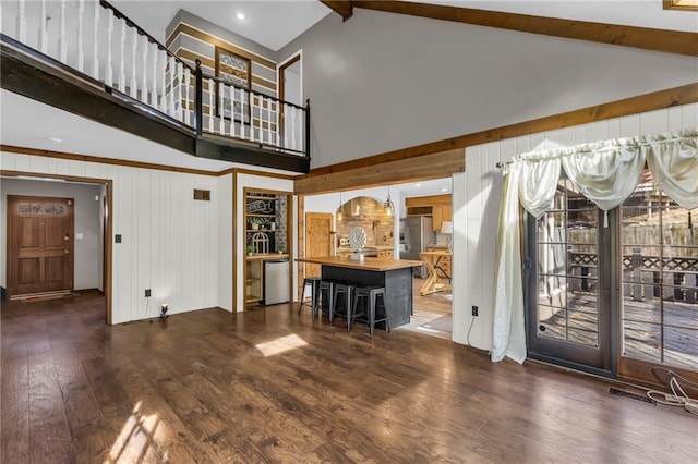 unfurnished living room featuring beam ceiling, high vaulted ceiling, and hardwood / wood-style floors